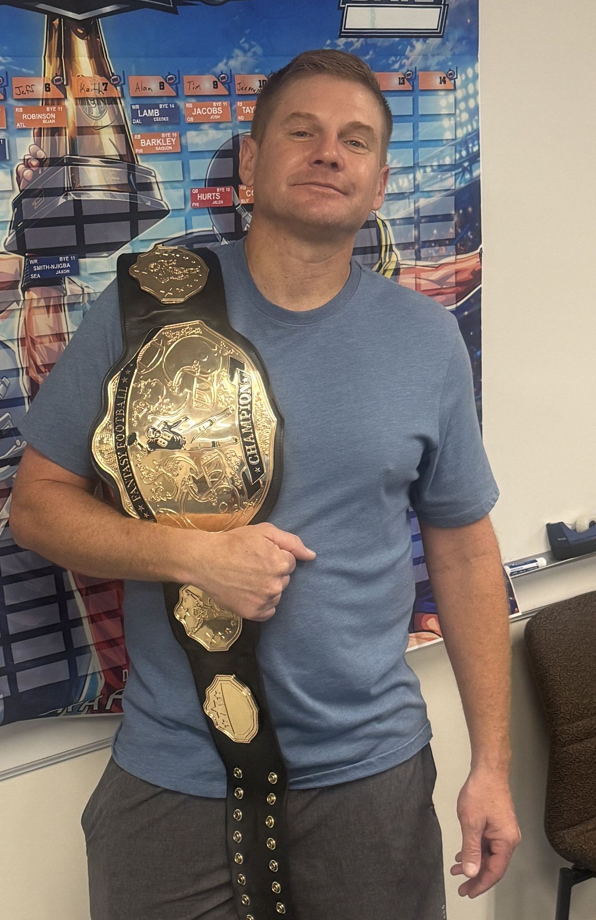 Justin Robinson holding the league championship belt in front of the draft board